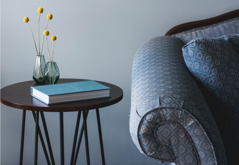 Side table with a book and a vase next to an armchair